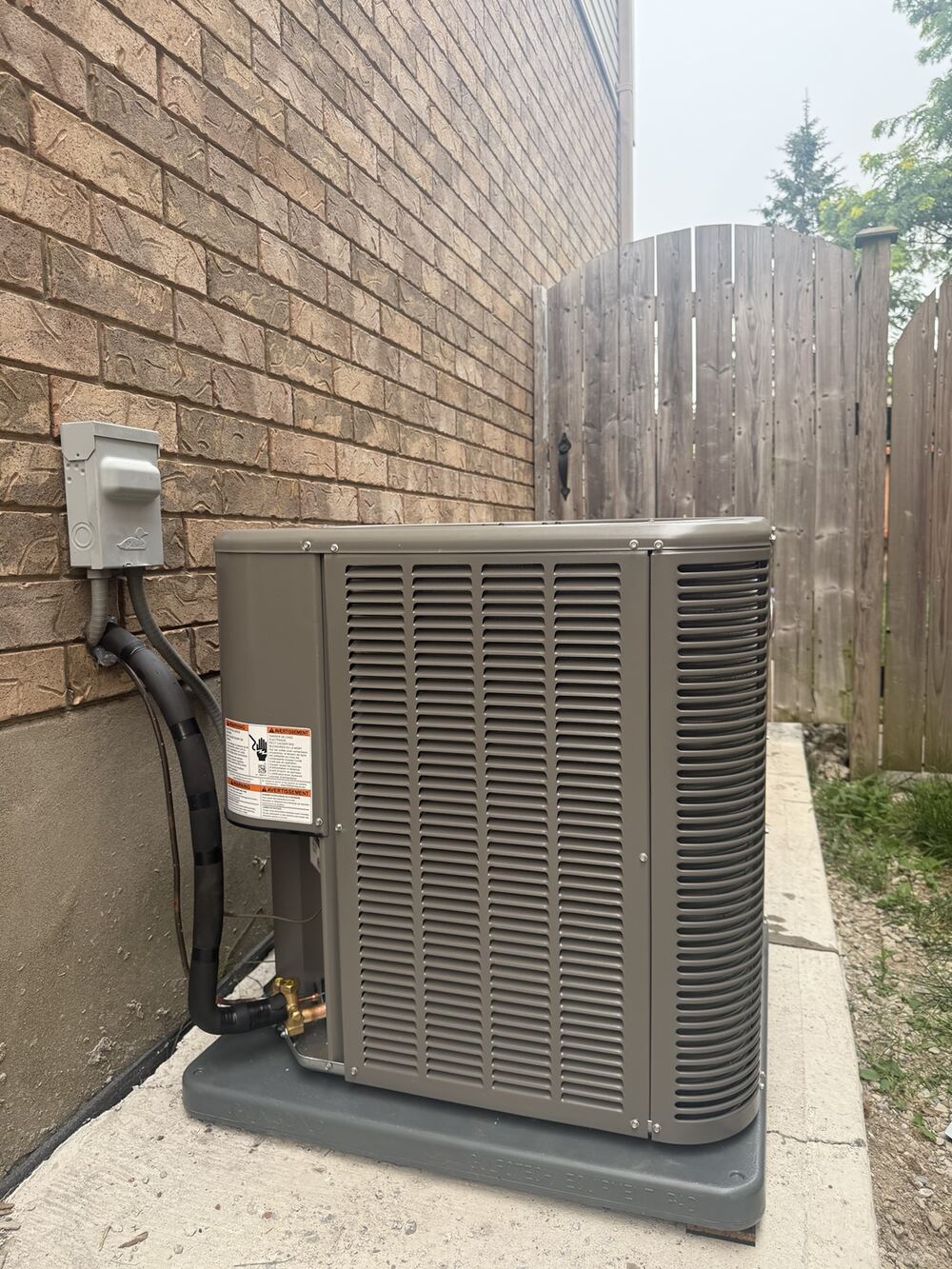 Outdoor air-conditioning condenser professionally installed beside a brick home