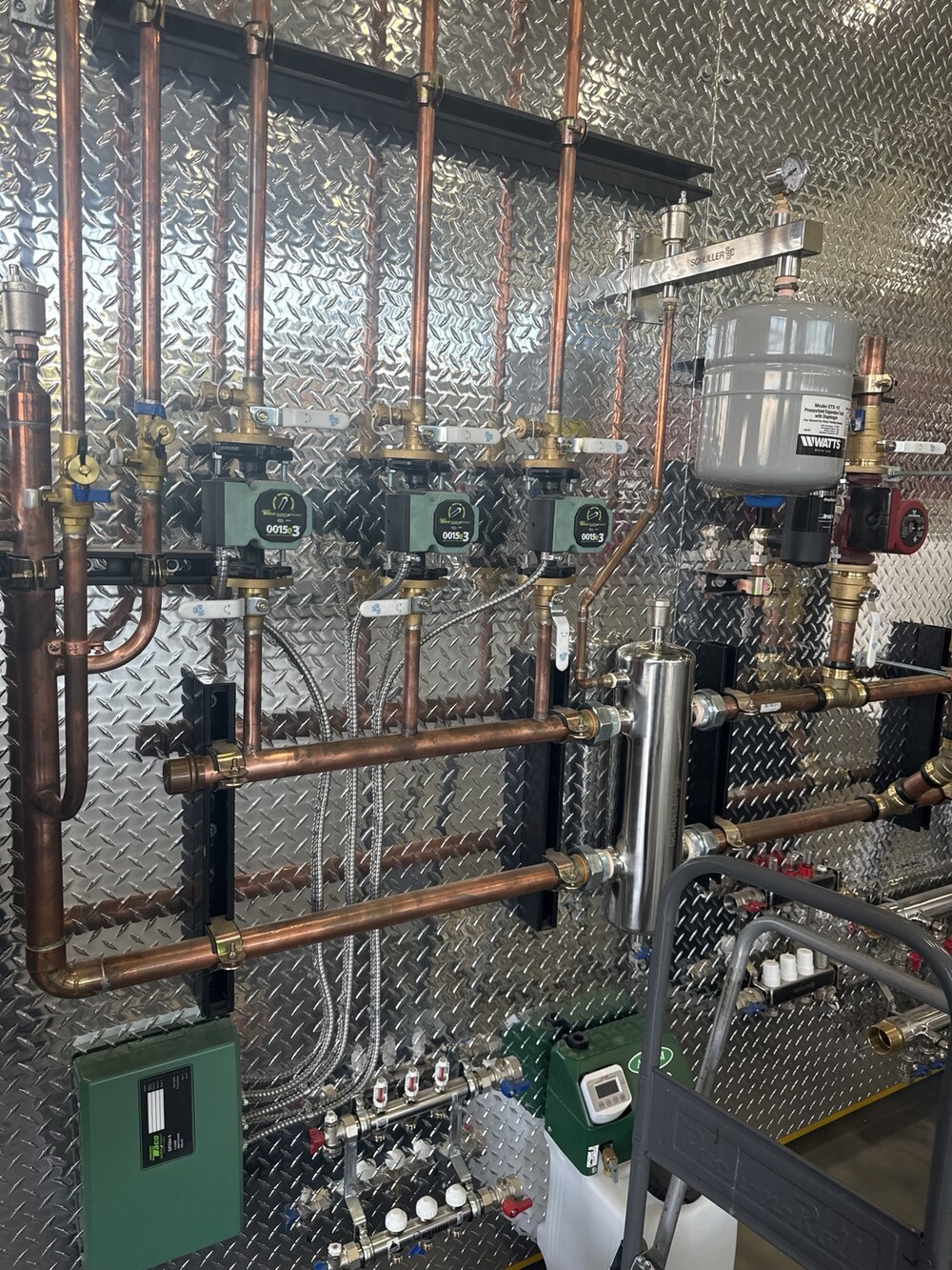 Airmaxx multi-zone hydronic in-floor heating installation with copper piping circulator pumps expansion tank and manifolds